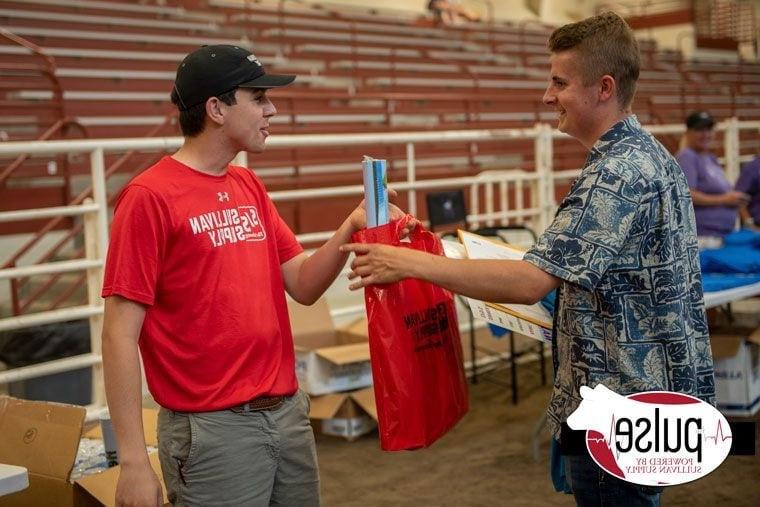 BHC graduate handing bag of supplies from sullivan supply to man